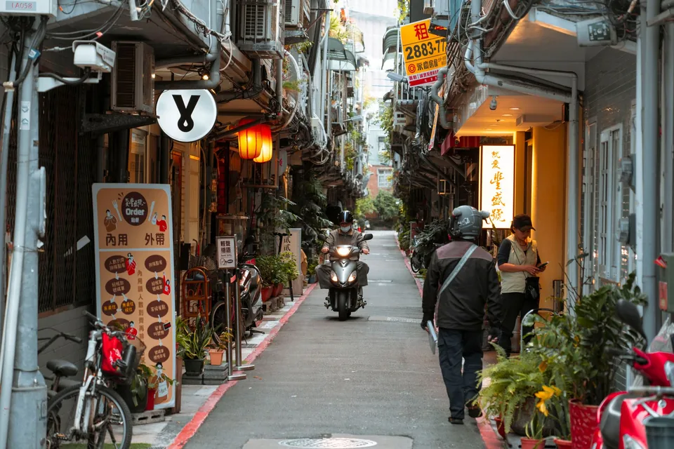 巷弄內小吃店家高掛燈籠,行人與機車穿梭