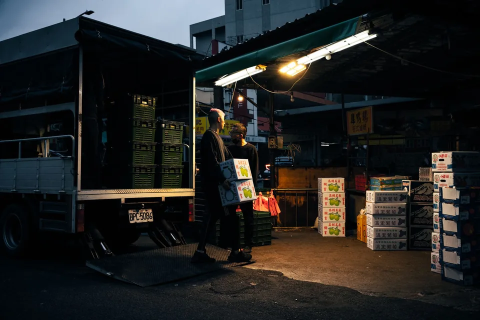 夜市生鮮攤前工人搬運進貨紙箱