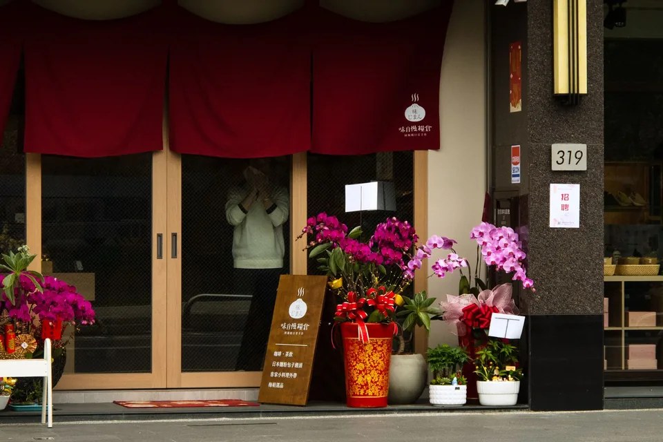 店門口擺滿開幕賀花與紅色布簾