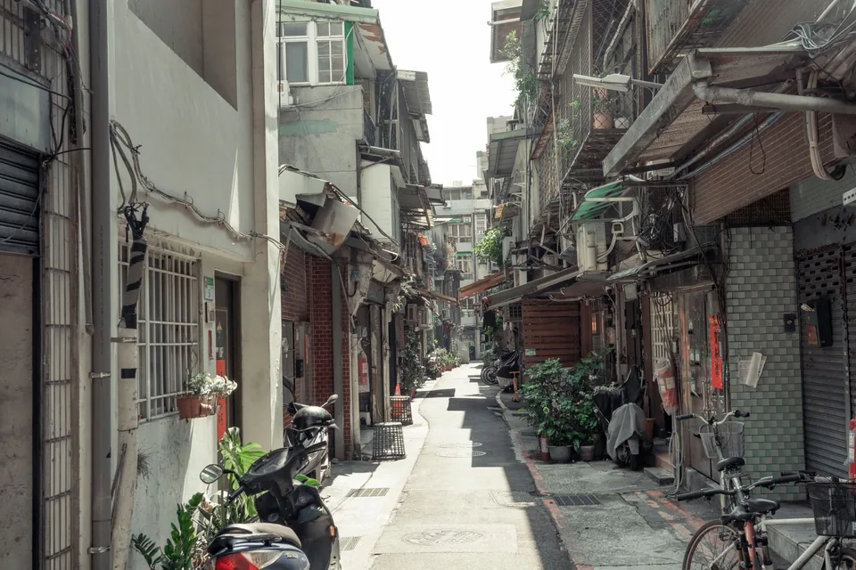 台灣老式街屋巷弄，兩側停放機車